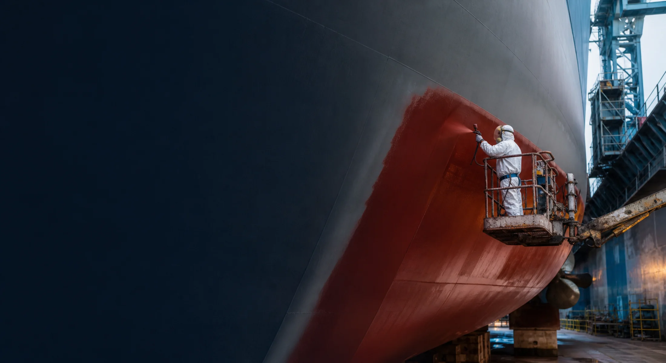 Kuru havuzdaki gemi gövdesine antifouling marin boya uygulayan uzman